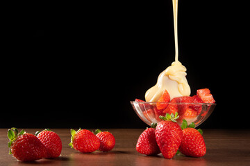 strawberries, crystal bowl with strawberries and condensed milk on a table, black background, select