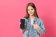 white girl 10 years old in a blue denim jacket with a smartphone in her hands on a pink background