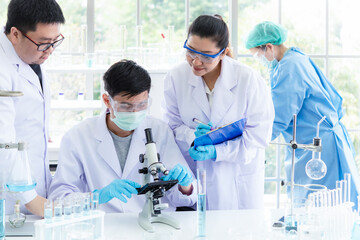 team work asia woman and man scientists analyzing study data and evaluating microscope success for w