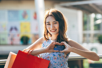 Wall Mural -  Young adult asian woman holding credit card and shopping bags.