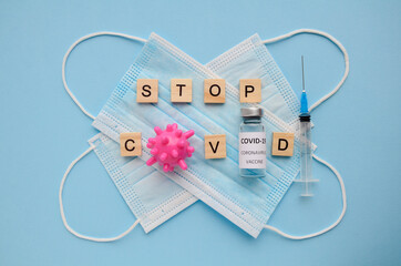 Two medical masks, syringe, vaccine bottle on blue background. Inscription stop covid. Cured of coronavirus, end of coronavirus concept. Concept of vaccination, vaccine. Medical flatlay.