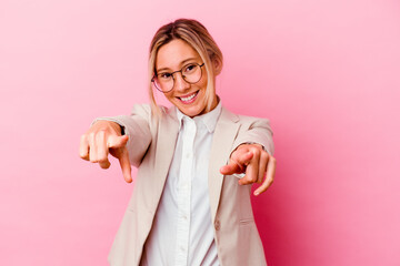 young caucasian mixed race business woman isolated on pink background cheerful smiles pointing to fr