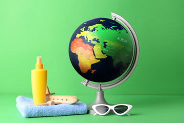 Globe and beach accessories on color background