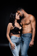 © LIGHTFIELD STUDIOS - Brunette woman hugging muscular man in jeans isolated on black