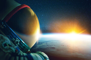 Poster - Astronaut in a space suit with a helmet in space with the blue planet earth and rays of sunsets. Spaceman in outer space travel, concept