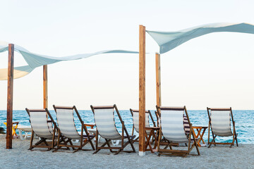 Summer beach background, scene with chairs, blue sea and sand, sunrise on the empty beach