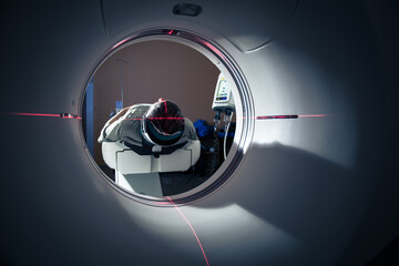 Senior man going through a Computerized Axial Tomography (CAT) Scan medical test/examination in a modern hospital (color toned image; shallow DOF)