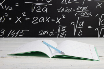 Notebook on blackboard background with mathematical formulas. Education concept.