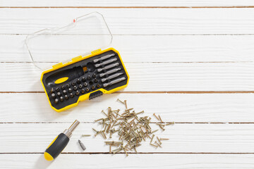 set of screwdrivers and metal screws on white wooden background