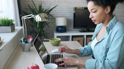 Wall Mural - Video of beautiful young afro business woman working with laptop sitting in the office at home.