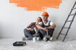 © Andrii Lysenko - home renovation concept, man and woman sit on the floor near the wall with orange stain.