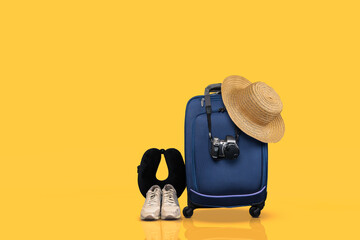 Blue wheeled hand luggage and essential travel items against yellow background.