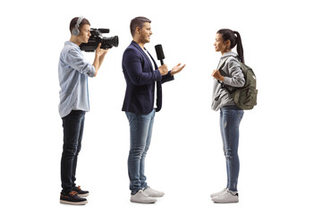 Wall Mural - Full length profile shot of a reporter with a microphone and a cameraman interviewing a female student