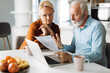 © Goran - Frustrated senior couple sitting at home and checking their home finances
