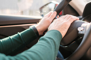 Close up mans hands on the wheel, driving a car. 