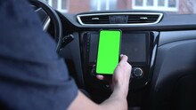A Male Driver Uses A Smartphone Vertically With A Green Screen, Holds A Phone In His Hand. Mockup For A Navigator Or Road Application. Zooms Out, Removes The Map. Build A Route On A City Map.