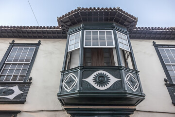 Facade of old building with a wooden balcony on a street in Spanish town Puerto de la Cruz on a sunny day. Puerto de la Cruz town, Tenerife, Canary Islands, Spain.