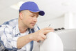 © auremar - portrait of mid-adult male technician repairing air conditioner