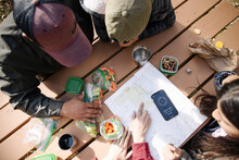 Family Looking At Map On Picnic Table In Forest