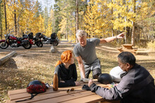 Bikers Looking At Digital Tablet At Picnic Table In Forest