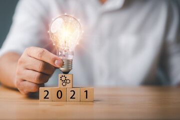 Poster - Businessman touching a bright light bulb. 2021 Concept of Ideas for presenting new ideas Great inspiration and innovation new beginning.