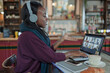 © Paul Bradbury/Caia Image - Young woman with headphones video chatting with colleagues in cafe