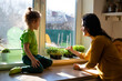 © oksix - Mother and son cutting microgreens at the kitchen