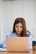© Prathankarnpap - Portrait of young female office worker working on laptop computer while sitting at office desk.