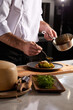 © Roman - Professional cook in uniform add some spices to dish, decorating delicious meal for guests in hotel restaurant. food, cooking concept