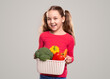 Happy girl carrying basket with fresh vegetables