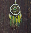 Beautiful handmade boho dreamcatcher with green, yellow and white feathers and medalion.