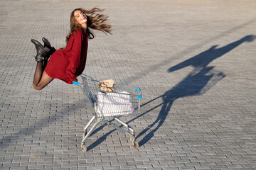 Shopping concept. Consumerism, sale and discount. Happy woman with shop cart outdoor.