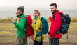 Cheerful friends with backpacks hiking in nature