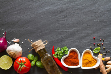 Wall Mural - Cooking background. Vegetables, herbs and spices on black slate