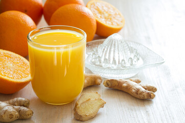 Wall Mural - Healthy and fresh orange juice with addition of ginger on white wooden table