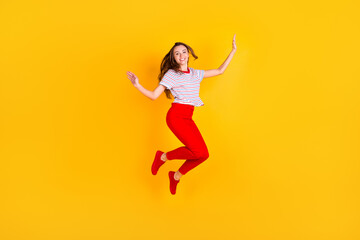 Wall Mural - Photo of cute adorable lady jump have fun wear striped shirt red trousers footwear isolated yellow color background