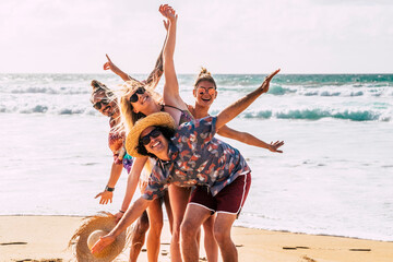 Group of happy caucasian young people boys and girls have fun and enjoy the beach in summer holiday vacation together laughing - cheerful men and women outdoor leisure activity - ocean background