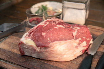 Closeup of a beautiful italian steak ready to be cooked on a barbeque. Appetizing piece of meat next to a pyre of firewood ready to be set on fire. Bbq, recreation, picnic, outdoors cooking concept.