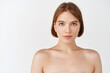 © Cookie Studio - Beauty face. Young girl with bare shoulders and natural facial makeup looking at camera. Woman with clean fresh skin, skincare cosmetics after effect, white background