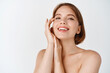 © Cookie Studio - Skin care beauty. Smiling natural woman with naked shoulders and healthy clean and fresh skin, looking happy, touching cheek. Girl apply facial cosmetics, white background