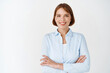 © Cookie Studio - Portrait of confident young female professional looking determined. Woman in office blouse cross arms on chest, smiling motivated, standing on white background