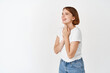© Cookie Studio - Beauty and happiness. Portrait of young woman looking left at logo, smiling and laughing carefree, standing in t-shirt and jeans, white background