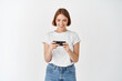 © Cookie Studio - Portrait of young woman watching video on smartphone, holding phone horizontally to play video game, white background