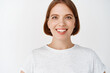 © Cookie Studio - Close-up portrait of smiling girl with short hair and t-shirt, looking cheerful at camera. Woman with hopeful eyes standing against white background
