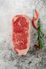 Wall Mural - Classic New York steak raw from grain-fed beef. Fresh grilled meat with seasonings and red pepper.