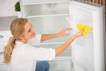 Wall Mural - Blonde housewife in white shirt cleaning the fridge