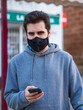 © David Martínez - Hombre joven con mascarilla usando su móvil