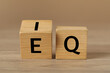 Cubes with letters E, I and Q on wooden table