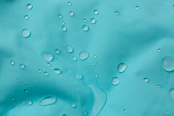 Turquoise waterproof fabric with water drops as background, closeup