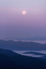 Wall Mural - The full moon setting at dawn over Shenandoah National Park as the valleys are filled with fog during sunrise.